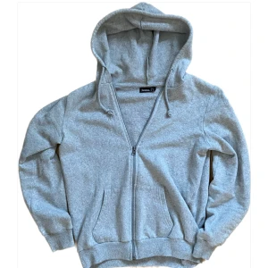 Grå hoodie med dragkedja - Säljer en klassisk grå Huvtröja från Jerzees med dragkedja. I bra skick, säljer då den är för liten. Hör av dig vid intresse eller fundering, pris går att diskutera vid snabb affär!