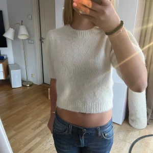 Vit stickad tröja - Säljer en mysig vit stickad tröja med korta ärmar och en croppad passform. Helt ny med prislappen kvar, säljer då den aldrig kommit till användning☺️☺️