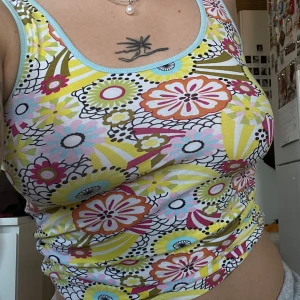 Färgglad blommig linnetopp från Kookai  - Säljer en färgglad linnetopp från Kookai med ett blommigt mönster i gult, rosa, blått och grönt. Toppen har en rund halsringning och är ärmlös med en kontrasterande randig insida. Perfekt för en somrig look! 🌼🌸