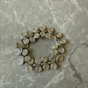 Unikt silverfärgat nytt armband med spiraldesign - Säljer ett unikt armband i silverfärg med en iögonfallande spiraldesign. Armbandet består av flera sammanlänkade spiraler som ger ett elegant och konstnärligt intryck. Perfekt för att ge en stilfull touch till din outfit.