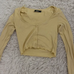 Gul ribbad kofta från bikbok - Säljer en söt gul ribbad kofta från bilbok.Den är croppad med knappar framtill och har långa ärmar. Perfekt för lager-på-lager-stil eller som ett lätt plagg för varmare dagar.