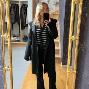 Svart kappa  - Säljer min svarta kappa från Bohoo. Storlek S. Lite tunnare kappa, perfekt till våren. Jättebra skick, har luva samt bälte. Säljer då jag har för mycket kappor/jackor