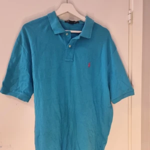 Ralph Lauren pike - Säljer en klassisk blå  pikétröja från Ralph Lauren med korta ärmar. Perfekt för en stilren och avslappnad look.               Vi har en deal då vi säljer 1 för 300kr 2 för 500 3 för 700