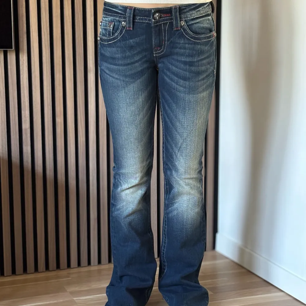 Lågmidjade bootcut jeans från Miss Me. Coola jeans med röda detaljer. Perfekt skick, se bild. Mått: Innerbenslängd: 85cm   Midjemått rakt över: 35cm Midjemått: 73cm Modellen är 166cm lång. Fler bilder finns. Skriv gärna ifall du har några frågor! 💗. Jeans & Byxor.