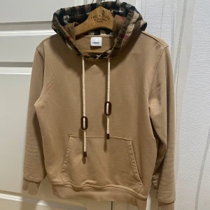Burberry Hoodie - Säljer nu denna stiliga och unika burberry hoodien för ett riktigt bra pris. Storlek S men passar Xs. Skick 8/10 (en liten fläck på baksidan som syns på bild 3). Det är bara att skriva vid funderingar eller liknande!