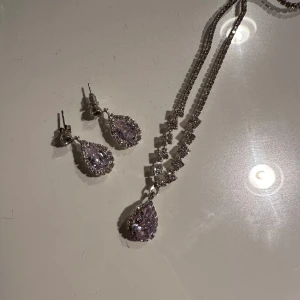 Glittrigt smyckeset med halsband och örhängen - Säljer ett smyckeset som består av ett halsband och matchande örhängen. Både halsbandet och örhängena har stora, droppformade stenar som verkligen fångar ljuset. Perfekt för fest eller nyår! 💎✨Silver. Inte äkta smycken 