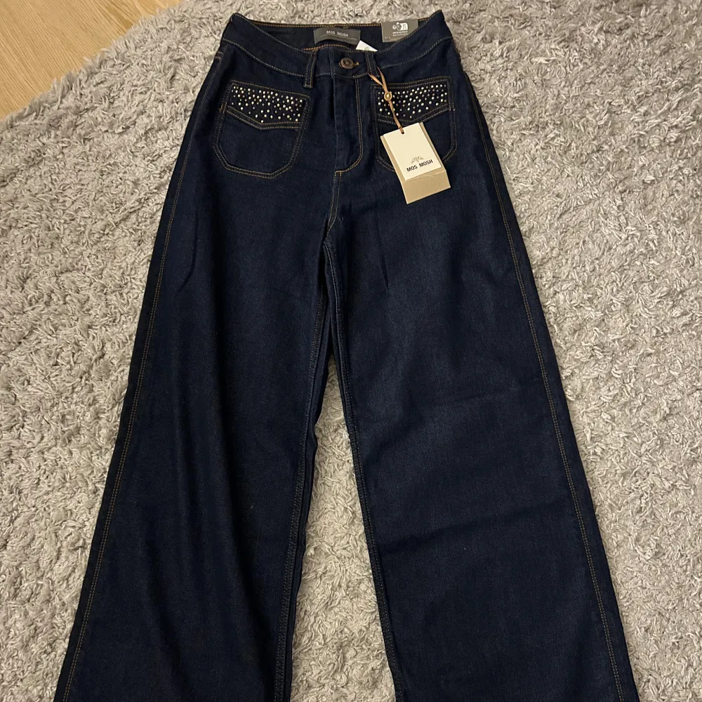 Säljer ett par mörkblåa Mos Mosh jeans🤍 Storlek 25, passar mig bra i midjan med alldeles för långa för mig, jag är 160cm! Helt oanvända med prislappen kvar🤍 Nypris 1700kr. Jeans & Byxor.