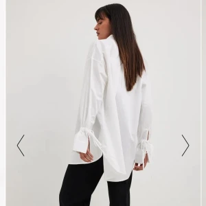 Vit skjorta - Cool vit oversized skjorta från NA-KD som tyvärr inte riktigt är min stil. Ärmarna är en snygg detalj som man knyta längt ned. Använd två gånger.