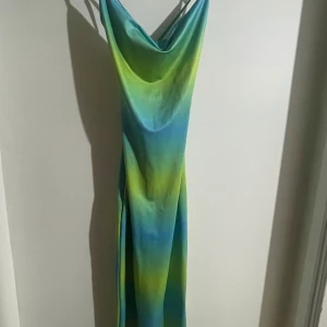 Långklänning med öppen rygg - En grön/blå långklänning (slipdress) med snöring i ryggen från NAKD. Materialet är stretchigt och lent, och passar perfekt till sommaren.