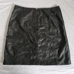 Svart fårskinnskjol Inwear - Snygg svart kjol i fårskinn med dragkedja framtill. Kjolen har en stilren design och är perfekt för att ge en edgy touch till din outfit. Den är tillverkad i ett mjukt och följsamt material som ger en bekväm passform. Slutar strax ovanför knät.