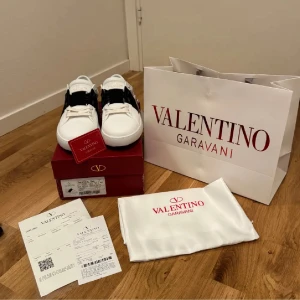 Valentino Garavani sneakers i vitt och svart - Snygga Valentino Garavani sneakers i vitt med en bred svart rem över ovansidan. Skorna kommer med originalförpackning kvitto och allt. Perfekta för en stilren look. Ny pris 4500kr mitt pris 1900kr.      Använda 1 gång!