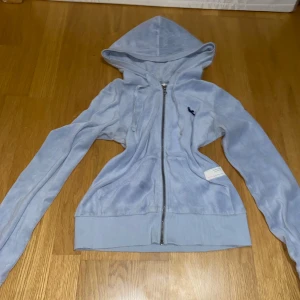 Ljusblå huvtröja från Odd Molly - Säljer en ljusblå huvtröja från Odd Molly med dragkedja och en stor rosett på ryggen. Tröjan har långa ärmar och ribbade muddar. Perfekt för en avslappnad stil. Några paljetter har fallit av och lite slitage på ärmarna som visat på sista bilden men inget man tänker på🩵