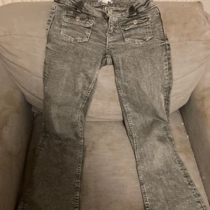 Grå jeans med bootcut - Snygga grå jeans med bootcut-stil och låg midja. De har två framfickor med knappar och två bakfickor. Perfekta för en avslappnad look.