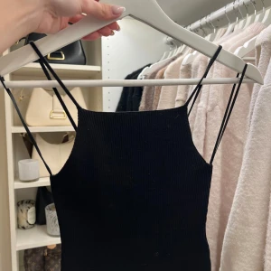 Svart ribbad linnetopp - Snygg svart ribbad linnetopp med smala axelband. Perfekt för en stilren look. Passar bra till både jeans och kjol.