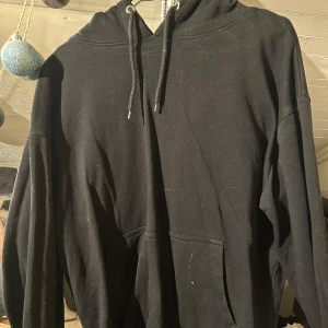 Svart hoodie från 157 - Säljer en klassisk svart hoodie från 157 i storlek S. Den har en bekväm passform med långa ärmar och en praktisk magficka. Perfekt för en avslappnad stil. Huvan har justerbara snören för extra komfort. Köparen betalar frakten.