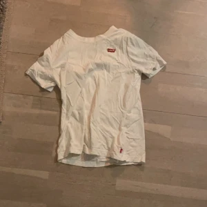 Vit t-shirt från Levi's - Säljer en klassisk vit t-shirt från Levi's med deras ikoniska logga på bröstet. T-shirten är kortärmad och tillverkad i mjuk bomull, perfekt för en avslappnad stil. Passar bra till jeans eller shorts för en enkel look. En väldigt liten storlek. 