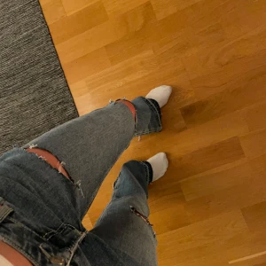 Blå jeans med slitningar - Snygga blå jeans med slitningar på knäna och låren. De har en klassisk femficksdesign och en knappgylf. Perfekta för en avslappnad stil. Bootcut❤️ midjemått ca 35-36 innerbenslängd ca 84, de passar heeelt perfekt för mej som är 172 och vill ha lite lite längre jeans😇 hör av er vid frågor eller diskussion om priset😇