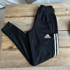 Svarta träningsbyxor från Adidas - Svarta  träningsbyxor från Adidas med de klassiska tre ränderna längs sidan. Perdekta för sport och träning. Storlek: xs🏋️‍♀️⚽️