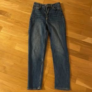 Blå jeans med hög midja - Snygga blå jeans från HM med hög midja och klassisk femficksdesign. De har en dragkedja och knapp framtill. Straight passform