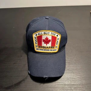 Mörkblå keps från Dsquared2 - Snygg mörkblå keps från Dsquared2. Kepsen har justerbar passform och text bak. Perfekt för en cool och avslappnad stil. Säljer den då jag inte använder den längre