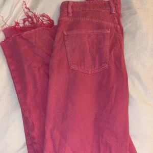 Rosa jeans från Zara - Snygga rosa jeans från Zara med fransiga benslut och klassisk femficksdesign. De har en knapp och dragkedja framtill. Perfekta för en färgglad stil.