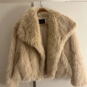 Beige pälsjacka från Laseti - Säljer en snygg beige pälsjacka från Laseti. Jackan har en fluffig och lyxig look med långa ärmar och en öppen front. Perfekt för att hålla sig varm och stilren under kyliga dagar. 🧥✨storlek S