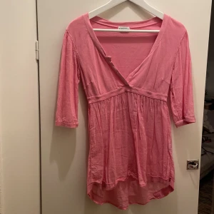 Rosa lite längre top från Hunkydory - Säljer en söt rosa top från Hunkydory. Topen har trekvartsärmar och en v-ringad design som ger en avslappnad look. Perfekt för en somrig dag eller en avslappnad kväll. 💖