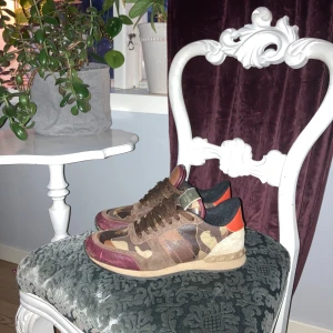 Camouflage sneakers från Valentino - Snygga sneakers i camouflage från Valentino med bruna och röda detaljer. Skorna har snörning och en unik design med orange häl. Perfekta för att sticka ut med stil. Pris är inte hugget hör av er vid frågor dem är äkta😉👍🍾👇