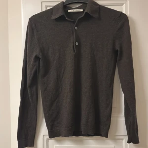 Brun långärmad tröja från A Day's March - Säljer en stilren brun långärmad tröja från A Day's March. Tröjan har en klassisk krage med knappar och är tillverkad i ett mjukt ull som ger en bekväm passform. Perfekt för en avslappnad men ändå snygg look.