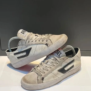  Diesel skor - Snygga grå sneakers från Diesel med snörning och en stilren design. Skorna har en diskret logga på sidan och en bekväm passform. Perfekta för en avslappnad stil.