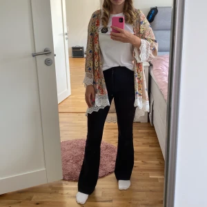 Blommig klänning med spetsdetaljer - Säljer en superfin blommig klänning i beige med färgglada blommor i rött, blått och gult. Klänningen har långa ärmar och vackra spetsdetaljer vid ärmslut och nederkant. Perfekt för vår och sommar!