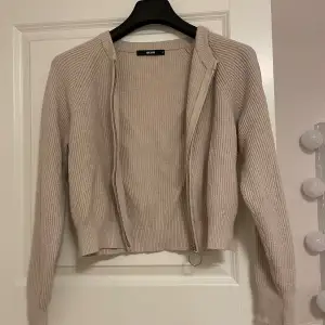 Säljer en superfin beige stickad kofta från BikBok. Den har en dragkedja framtill med en cool ringdetalj och är ribbad för en snygg look. Perfekt för höst och vinter när du vill hålla dig varm och stilren. Koftan är i storlek S och passar perfekt till både jeans och kjol. 🧥✨