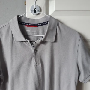Grå pikétröja från Race Marine - Säljer en stilren grå pikétröja från Race Marine. Den har en klassisk krage och knappar framtill. Perfekt för en avslappnad men ändå snygg look. Passar bra till både vardag och lite mer uppklädda tillfällen.