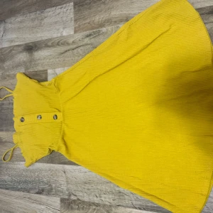 Gul klänning med knappar - Snygg gul klänning med knappar framtill och smala axelband. Perfekt för soliga dagar med sin ljusa färg och lätta material. Priset går att diskuteras 