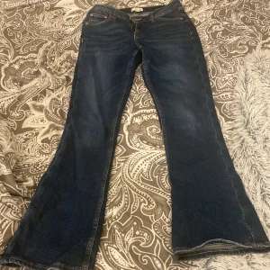Mörkblå bootcut jeans från Gina Tricot - Snygga mörkblå bootcut jeans från Gina Tricot. Klassisk femficksdesign med knapp och dragkedja framtill. Perfekta för en avslappnad stil med en touch av retro.