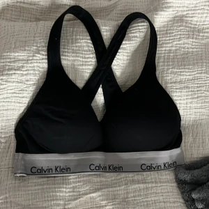 Svart sport-bh från Calvin Klein - Svart sport-bh från Calvin Klein med korsade axelband och elastiskt band. Aldrig använd och säljs pga används inte. Stolek M/M. Skriv för fler frågor eller bilder💓💓
