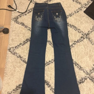 Blå bootcut jeans från Shein - Snygga blå bootcut jeans från Shein i storlek Petite XXS. Jeansen har hög midja och dekorativa broderier på bakfickorna. 