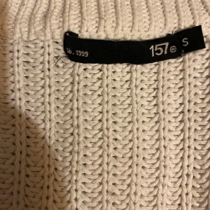 Vit och svart randig stickad tröja från 157 - Säljer en snygg vit stickad tröja från 157 med svarta ränder. Tröjan har en avslappnad passform och långa ärmar, perfekt för kyligare dagar. Den är både stilren och bekväm, ett måste i garderoben!