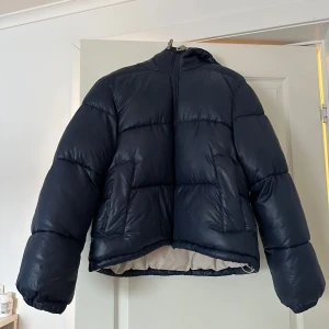 Marinblå dunjacka - Marinblå pufferjacka från H&M Egendesignad, cremevit insida. Väldigt fint skick - inga fläckar eller repor. Köpt för 700.