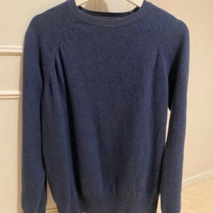 Blå tröja från Oscar Jacobson - Säljer en stilren blå tröja från Oscar Jacobson, tillverkad i Italien. Tröjan har en klassisk rund hals och långa ärmar, perfekt för kyligare dagar.