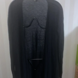 Svart cardigan från H&M - Säljer en stilren svart cardigan från H&M. Den har en öppen design och är perfekt för lager-på-lager-stil. Passar bra till både vardag och mer uppklädda tillfällen. Ett mångsidigt plagg för garderoben!