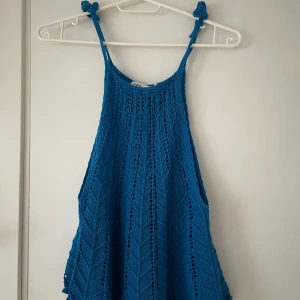 Blå stickad linnetopp - Snygg blå stickad linnetopp med ett luftigt mönster. Perfekt för varma sommardagar. Toppen har smala axelband och en avslappnad passform.