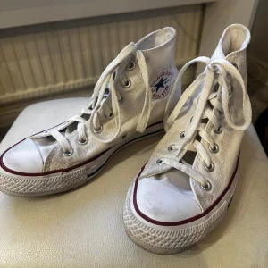 Vita Converse All Star sneakers - Äkta vita höga Converse skor, använt de några gånger och är i bra skick. I fjärde bilden kan man se en liten fläck men har ej prövat att tvätta den men kan vara möjligt att få bort den. Sedan sista bilden så är det innanför snörningen som det finns några fläckar men det syns inte när man har knutit åt dem! 