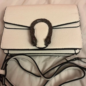 Vit axelväska med ormsmycke - Jätte fin vitt väska aldrig använt den. Kan mötas upp i Stockholm om man ej vill frakta 