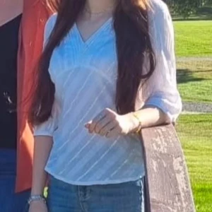 Vit blus från H&M - Säljer en elegant vit blus från H&M med v-ringning och knappar framtill. Blusen har trekvartsärmar och ett subtilt randigt mönster. Perfekt för en stilren look. Endast använd vid fotning❤️