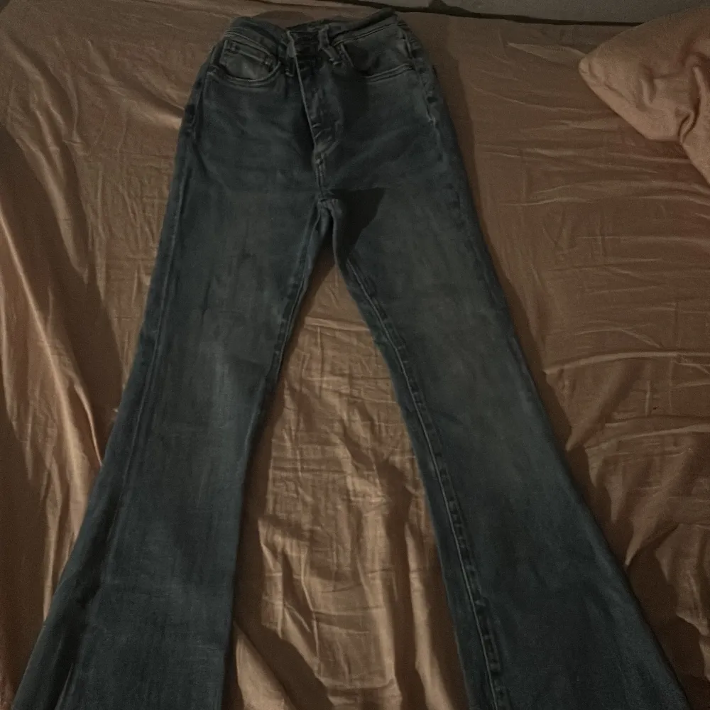 Snygga blå bootcut jeans med en klassisk look. De har en lätt utsvängd stil och råa kanter vid bensluten för en trendig touch. Perfekta för en avslappnad stil. Ett av benet är klippta längst ner. Lite stjärnor på benen.. Farkut & Housut.