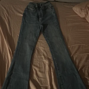 Blå bootcut jeans - Snygga blå bootcut jeans med en klassisk look. De har en lätt utsvängd stil och råa kanter vid bensluten för en trendig touch. Perfekta för en avslappnad stil. Ett av benet är klippta längst ner. Lite stjärnor på benen.