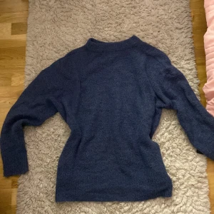 Mörkblå stickad tröja - Säljer en mysig mörkblå stickad tröja med långa ärmar. Perfekt för kyliga dagar och ger en stilren look. Passar bra till både jeans och kjol.