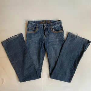 Blå jeans med snygga fickor - Bra skick, lite trasiga längst ner. Midja rakt över: 35 cm. Hela vägen runt: 70 cm. 