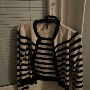 Randig kofta från H&M Divided - Säljer en snygg randig kofta från H&M Divided i svart och vit. Koftan har långa ärmar och en öppen design utan knappar. Perfekt för lager-på-lager-stil och passar till många olika outfits.